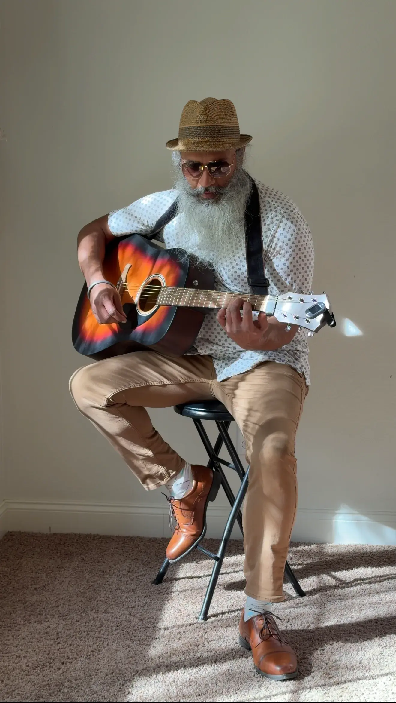 Gurpreet seated and playing an acoustic guitar