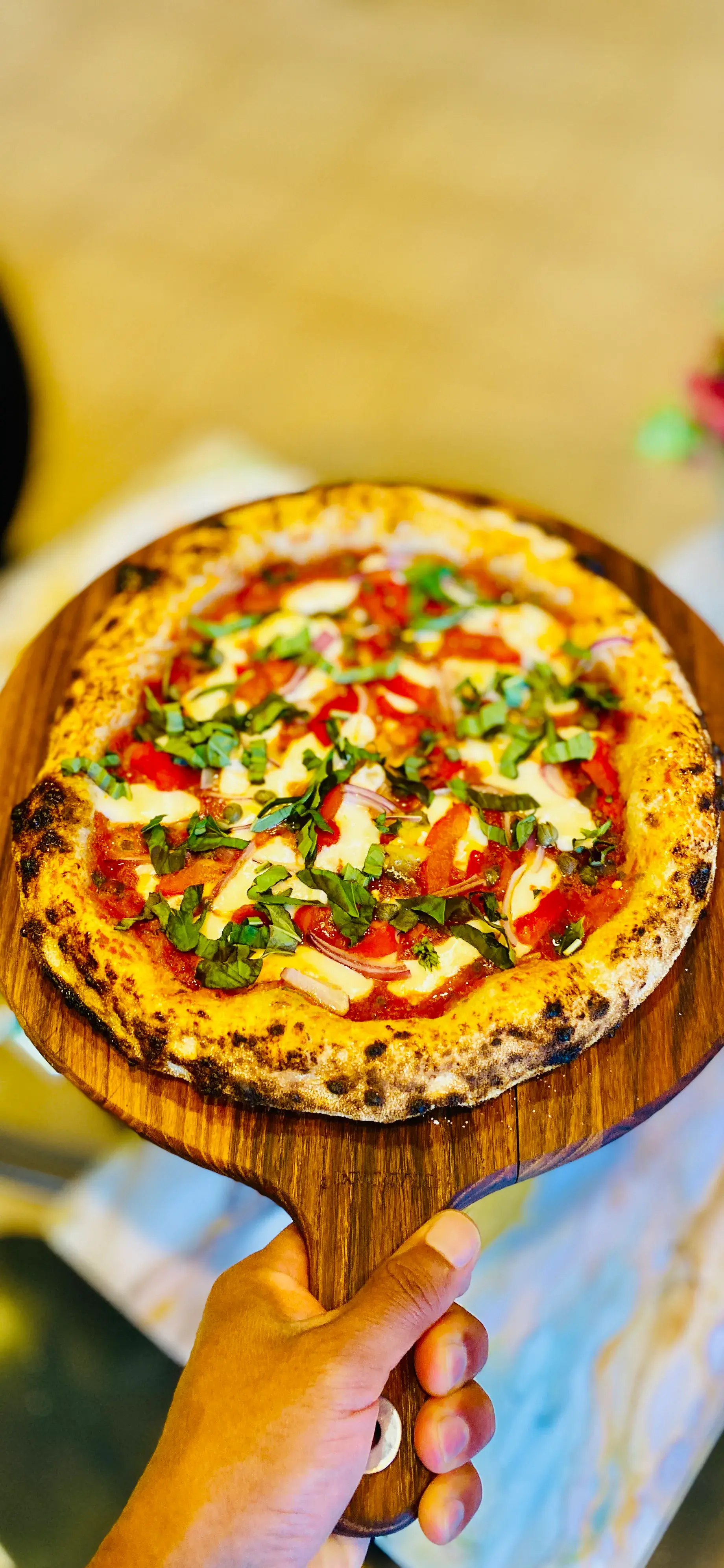 A freshly baked handmade pizza presented on a wooden peel