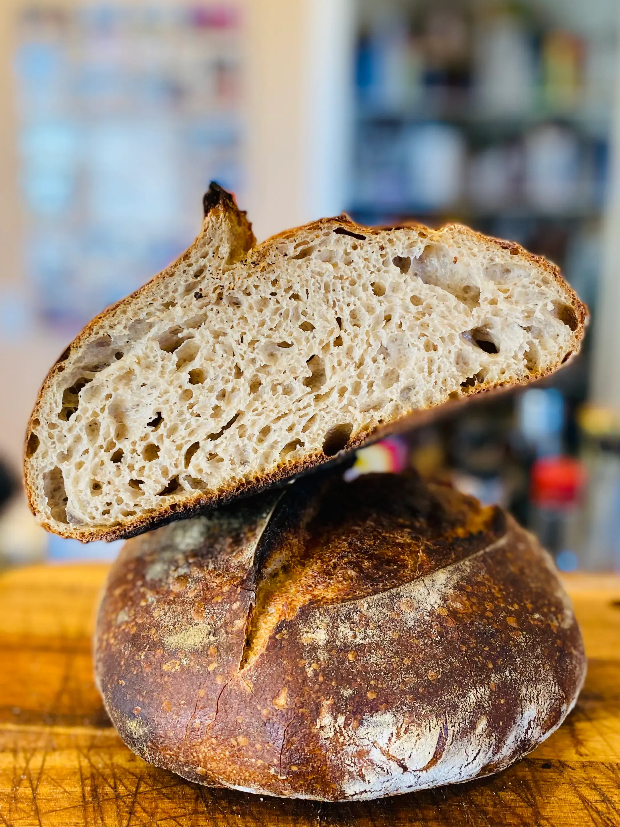 A rustic sourdough loaf with a cut slice showing its crumb